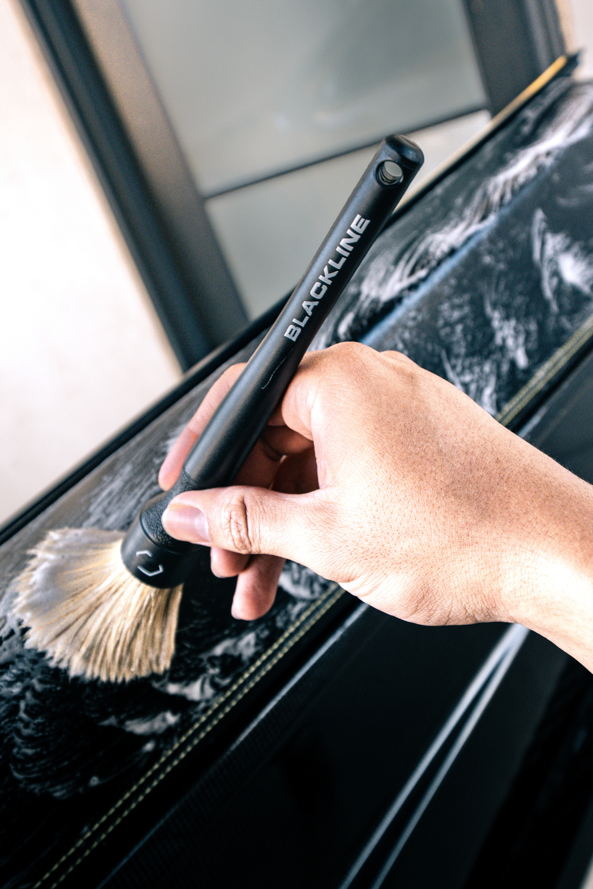 Hand applying Blackline Blackout from the kit to vehicle exterior.