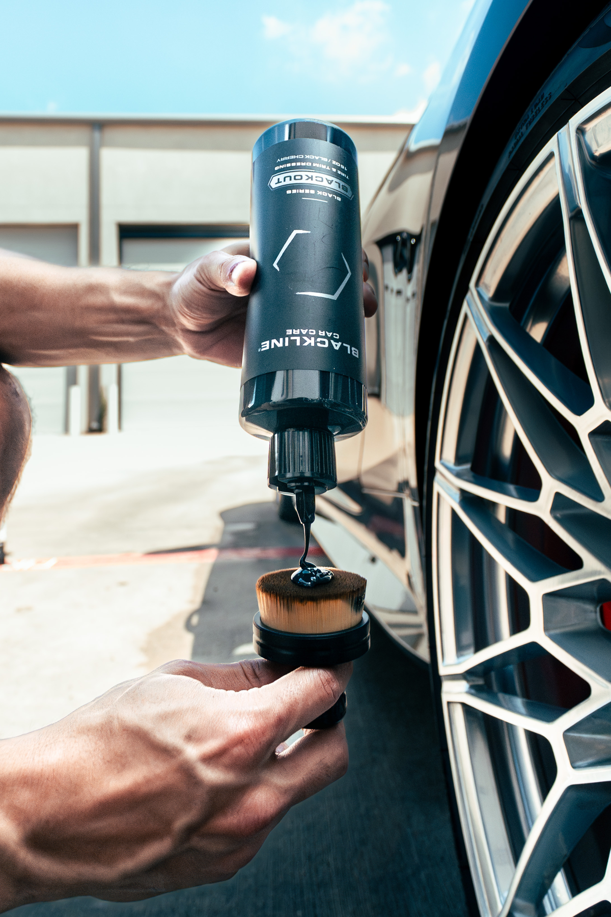 Person applying Blackline Blackout trim and tire dressing to a tire sidewall with an applicator pad.