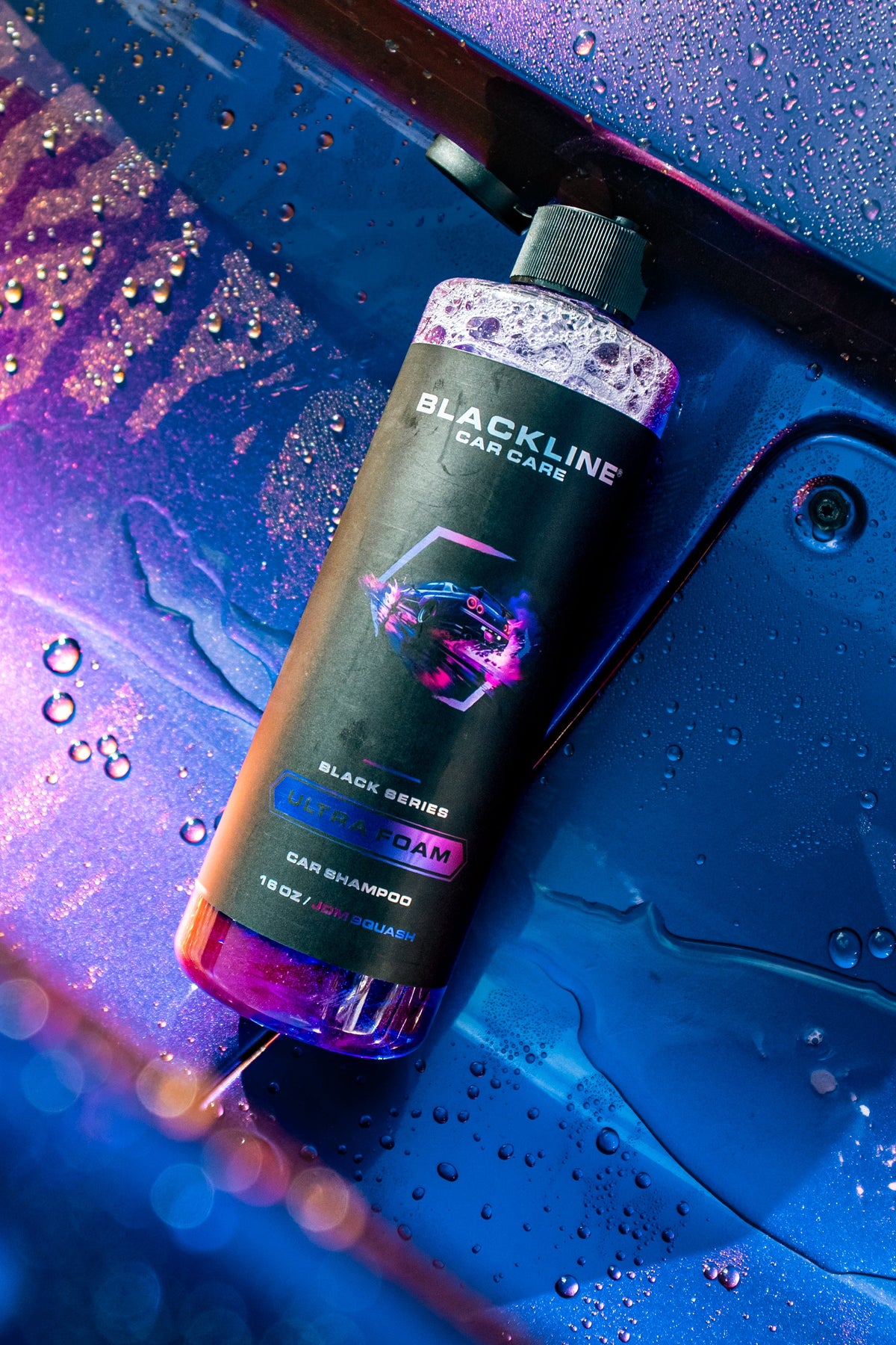 Blackline Ultra Foam JDM Squash bottle laying on a wet car surface with bokeh light reflections.