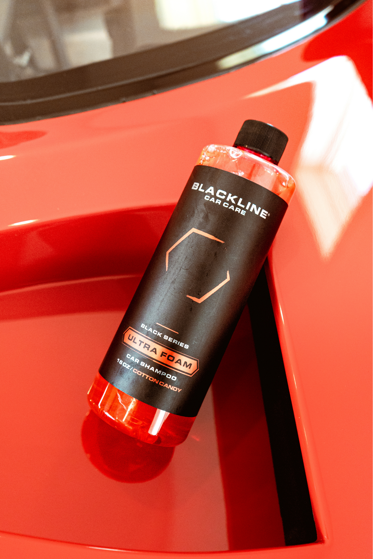 Blackline Ultra Foam Cotton Candy 16oz bottle resting on the hood of a red Ferrari F40.