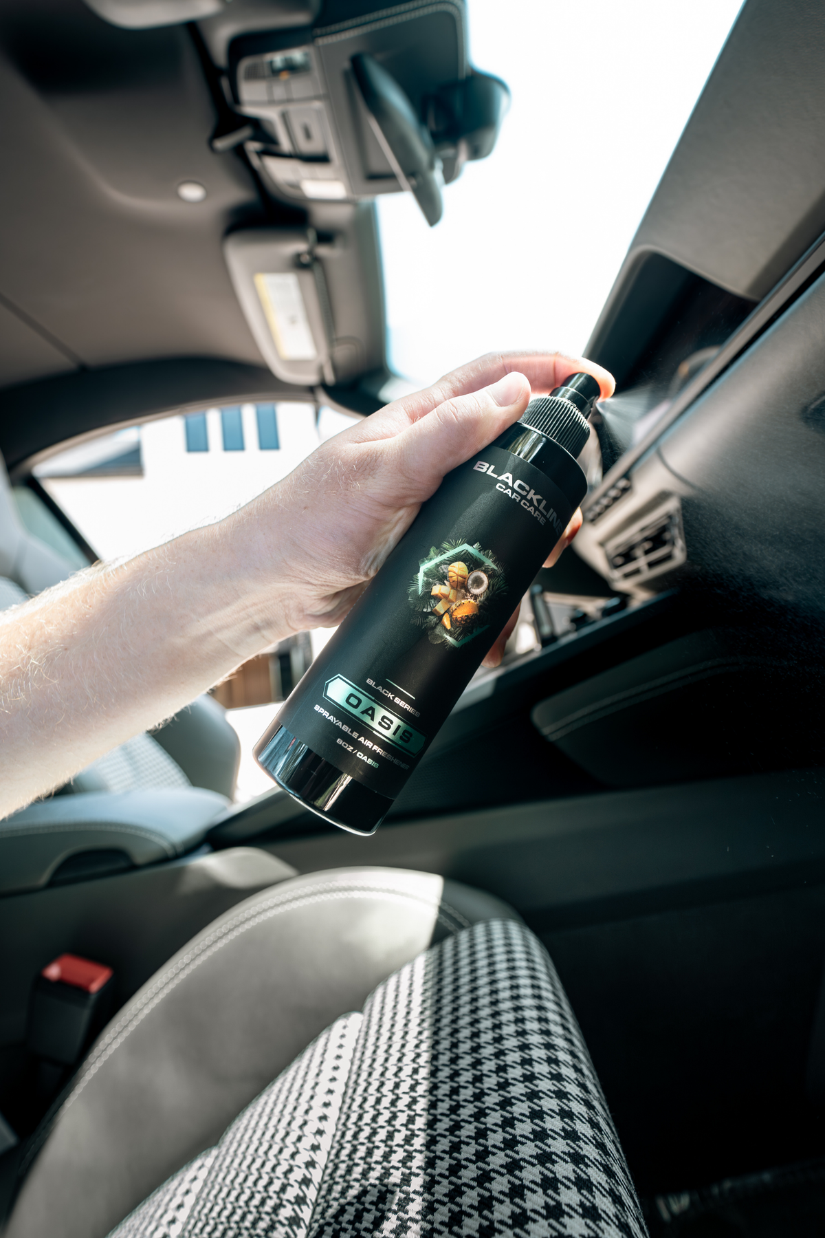 Blackline 8oz air freshener spray in Oasis scent, black bottle photographed at an angle.