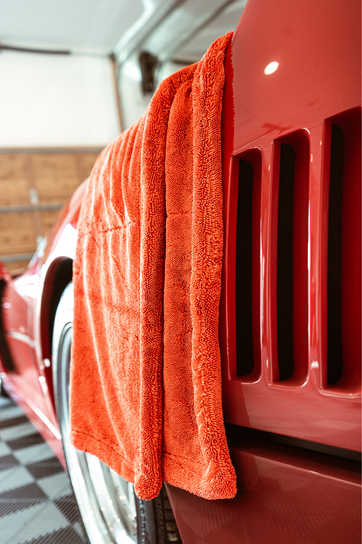 A bright red Blackline twisted-loop drying towel draped over the front fender of a red Ferrari F40.