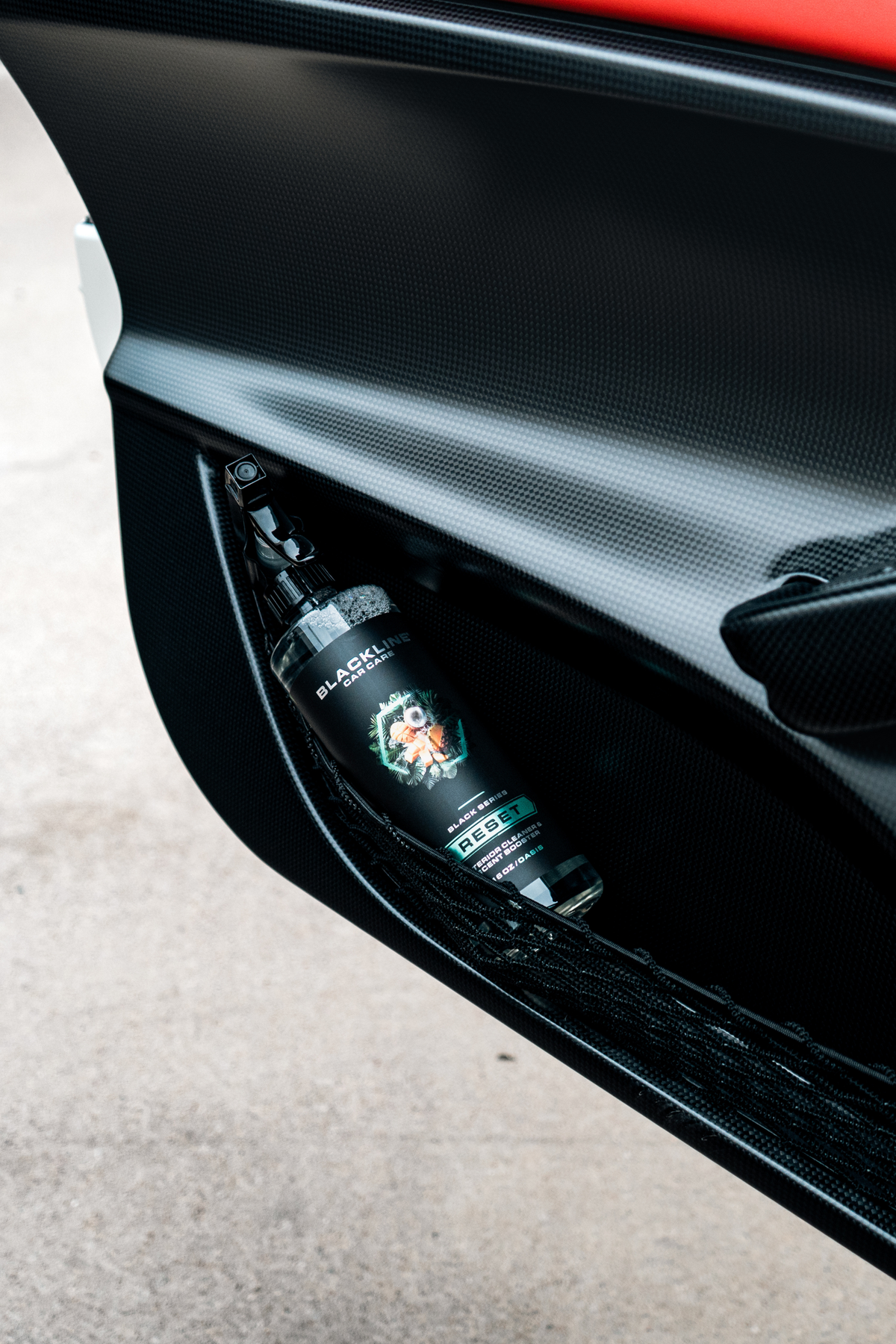 Blackline Reset Oasis interior cleaner applied to a car door panel.
