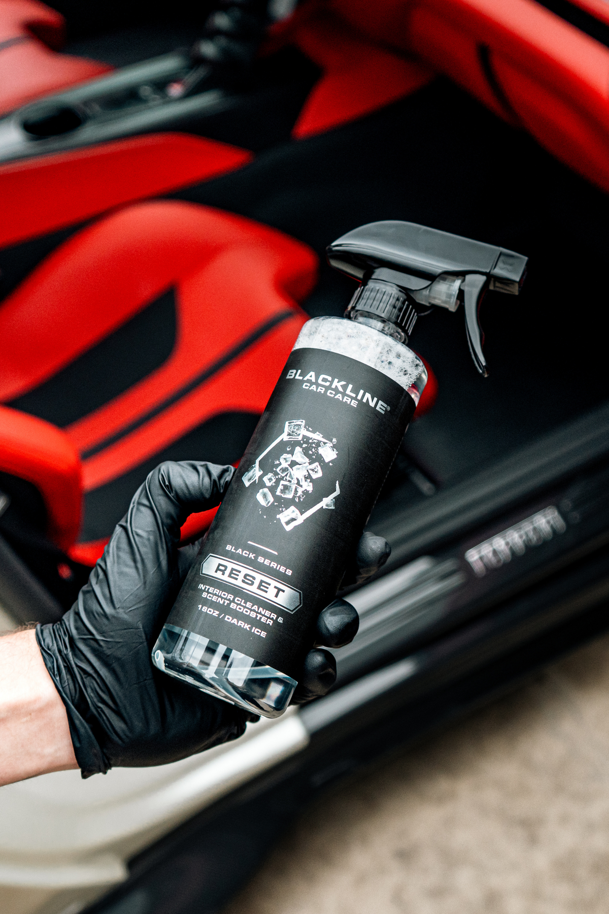 Hand holding Blackline Reset Dark Ice scented interior cleaner spray bottle.