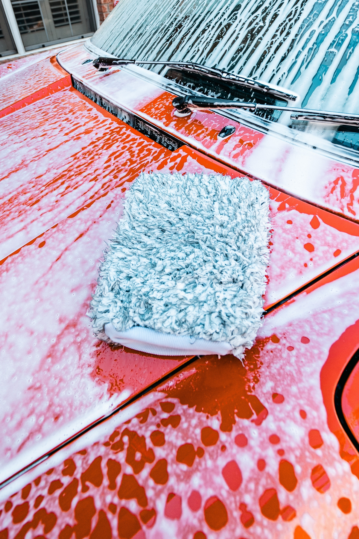 Hand washing a car body with the Blackline Microfiber Wash Mitt and foam.