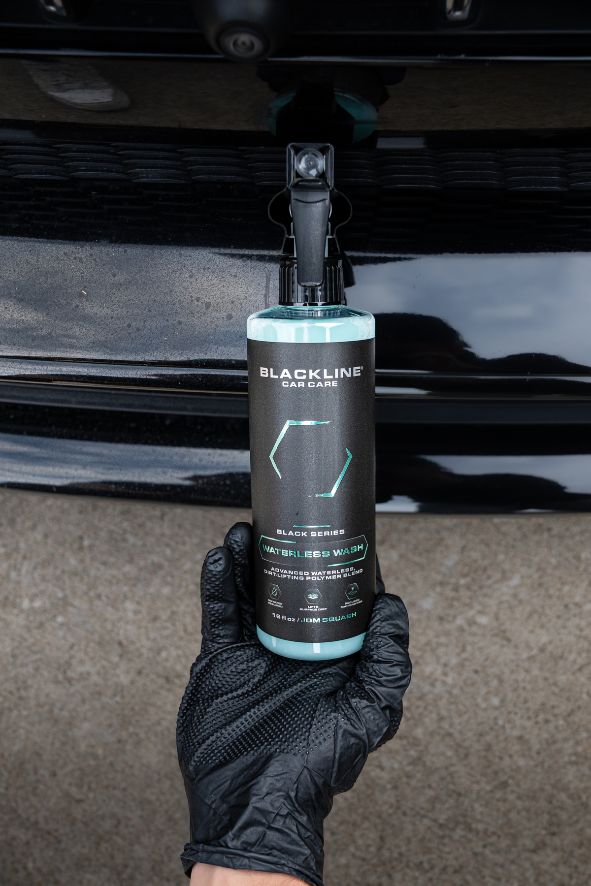 Detailer wiping a car panel with microfiber towel after applying Blackline Waterless Wash