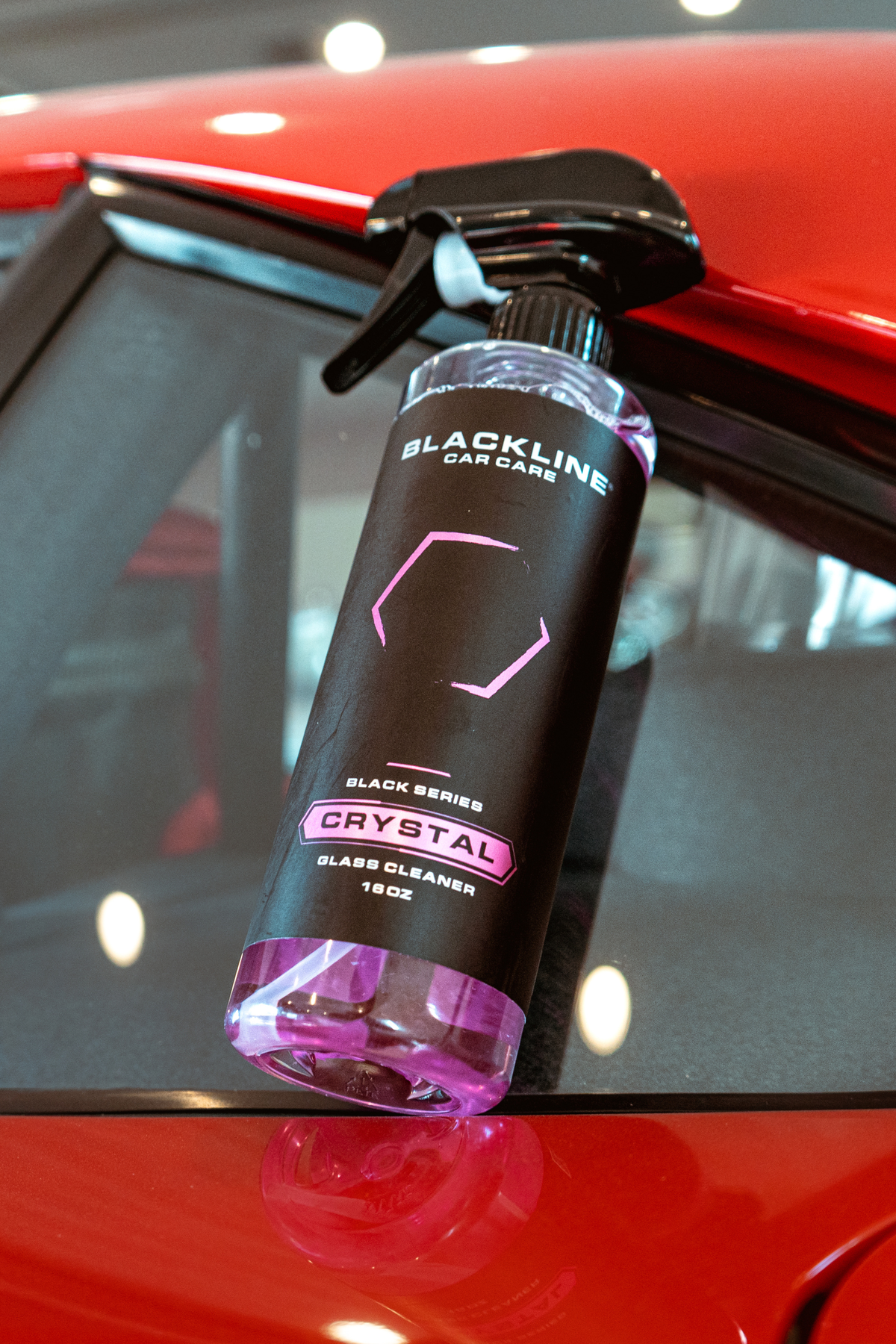 Hand wiping a car window with Blackline Crystal Glass Cleaner.