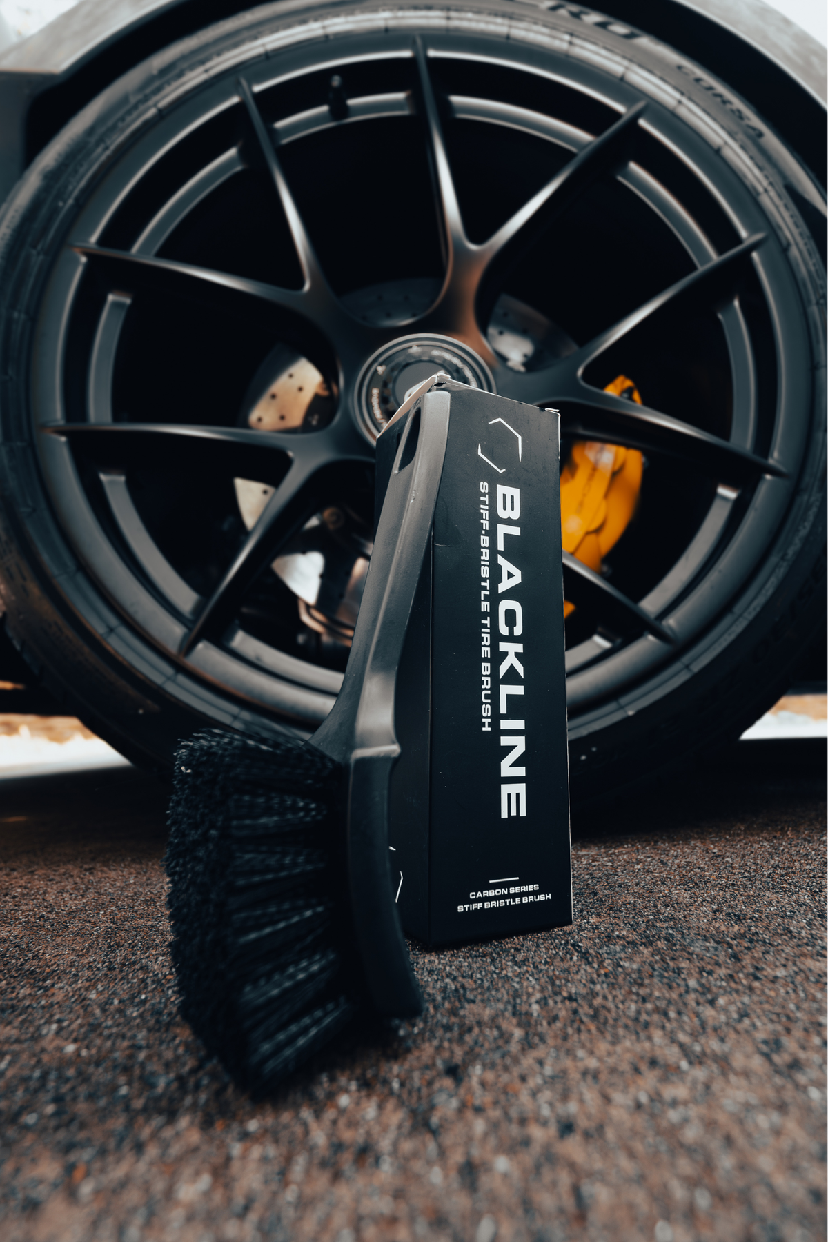 Stiff bristle tire brush being used to scrub a tire sidewall.