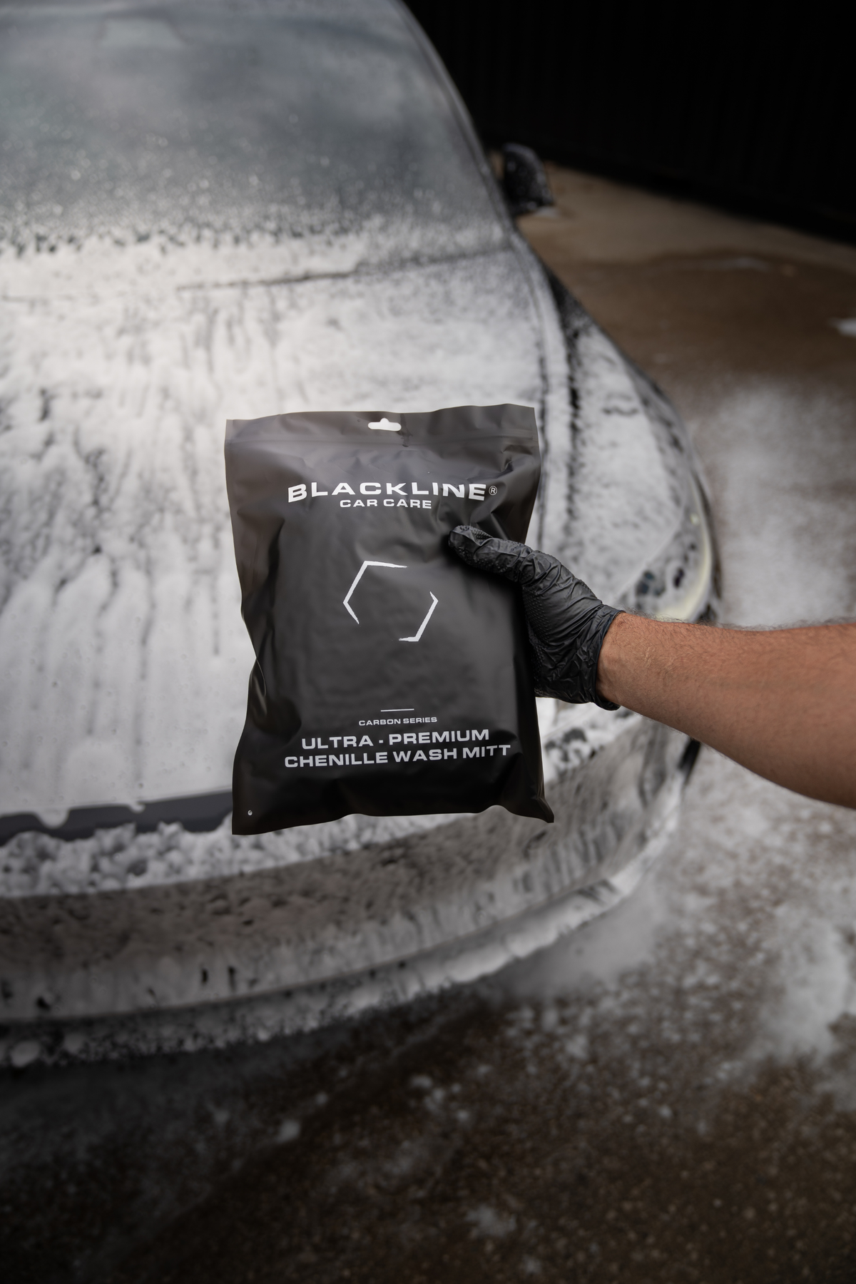 Blackline Chenille Wash Mitt draped over a shiny black car door panel.