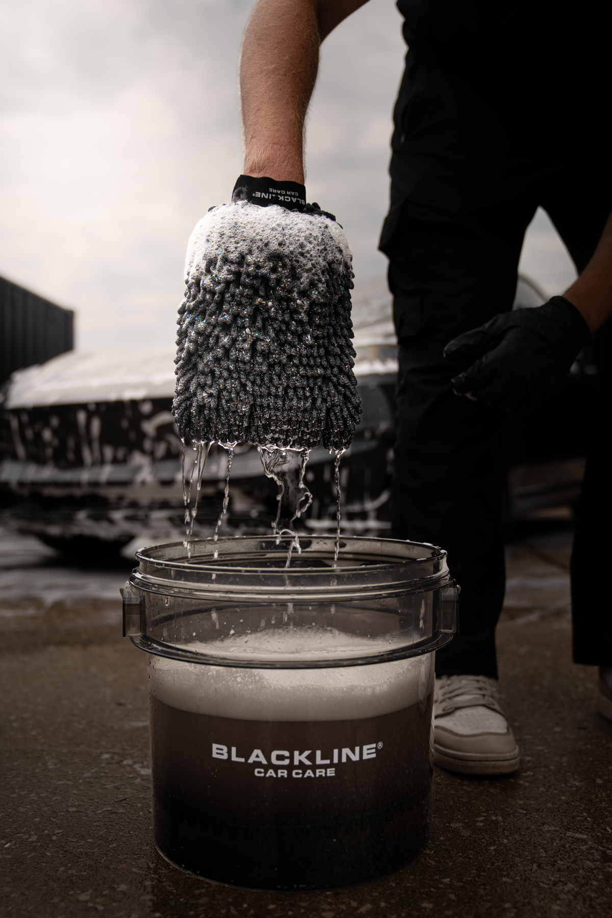 Blackline Chenille Wash Mitt in use safely lifting dirt from a dark car door.