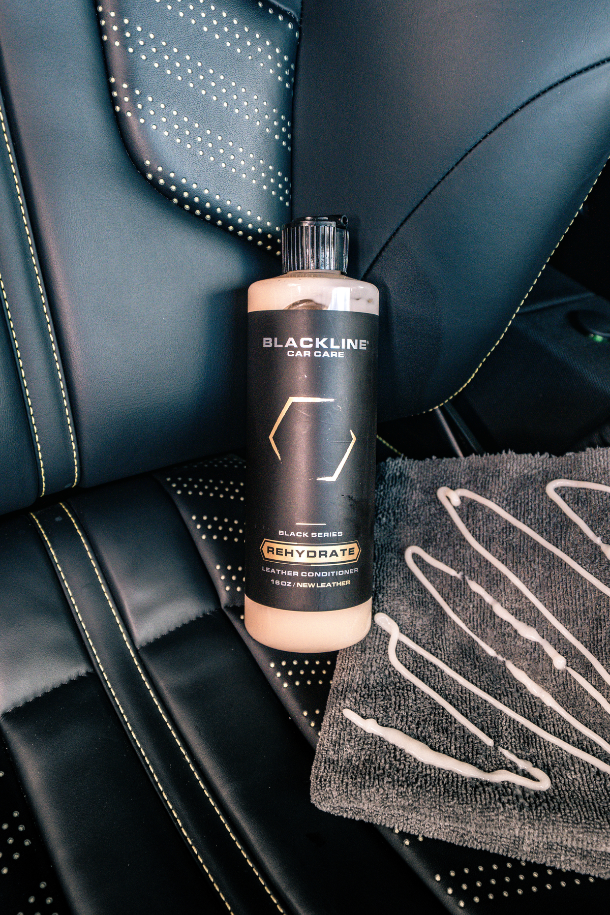 Blackline Gentle APC bottle on a leather seat alongside a black microfiber towel.