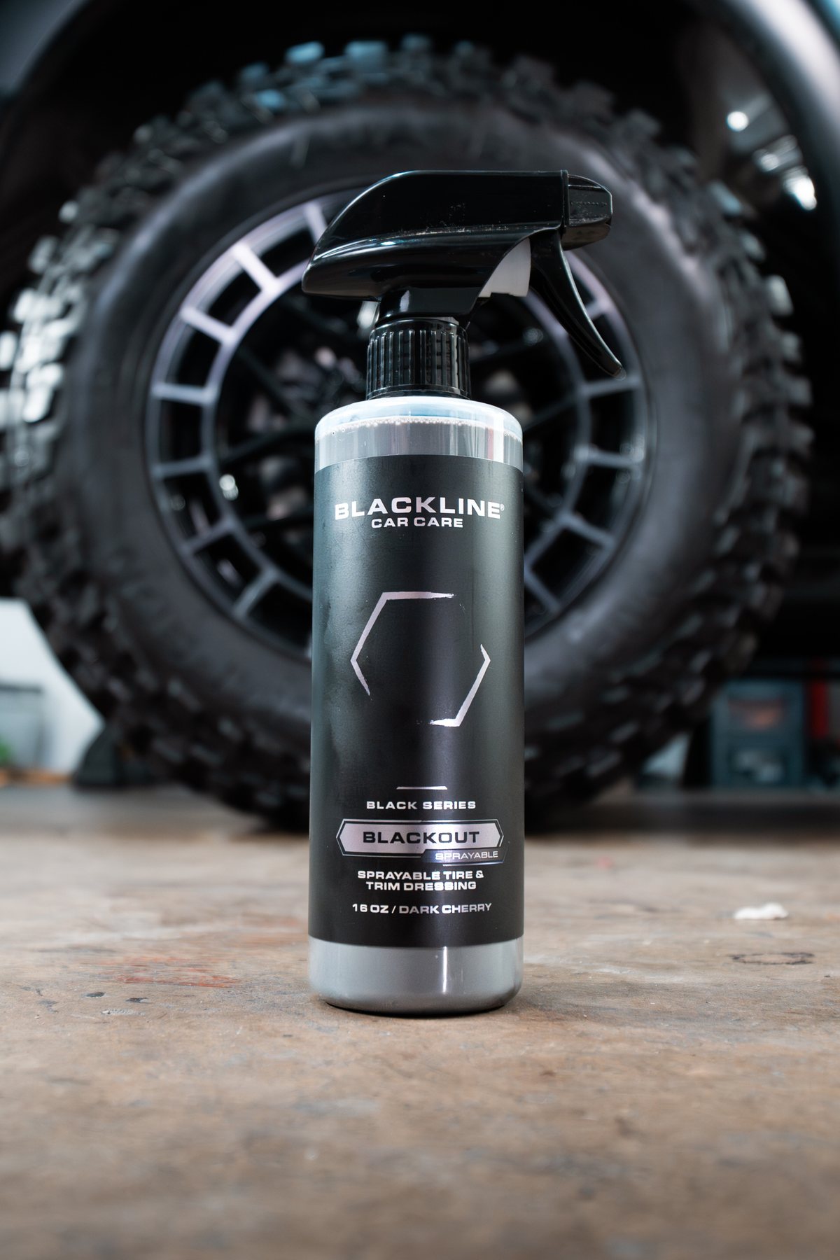 Blackline Blackout trim and tire dressing bottle in front of a rugged off-road tire.