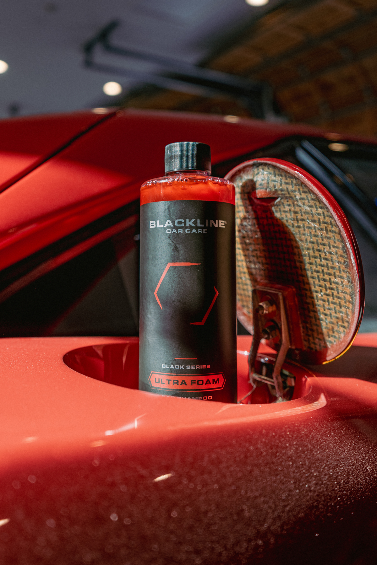 Blackline Ultra Foam Cotton Candy 16oz bottle resting on the rear of a red Ferrari F40.