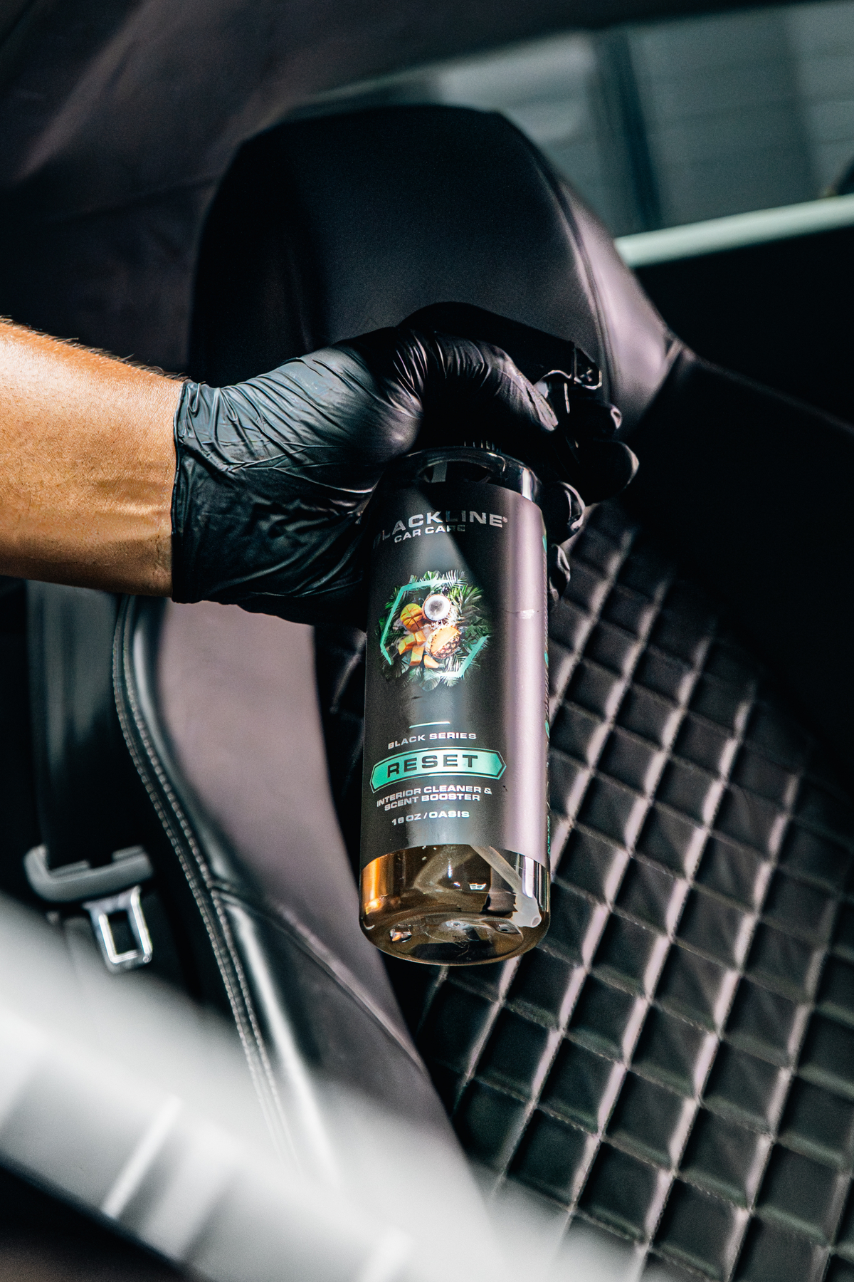 Hand spraying Blackline Reset Oasis interior cleaner during detailing.
