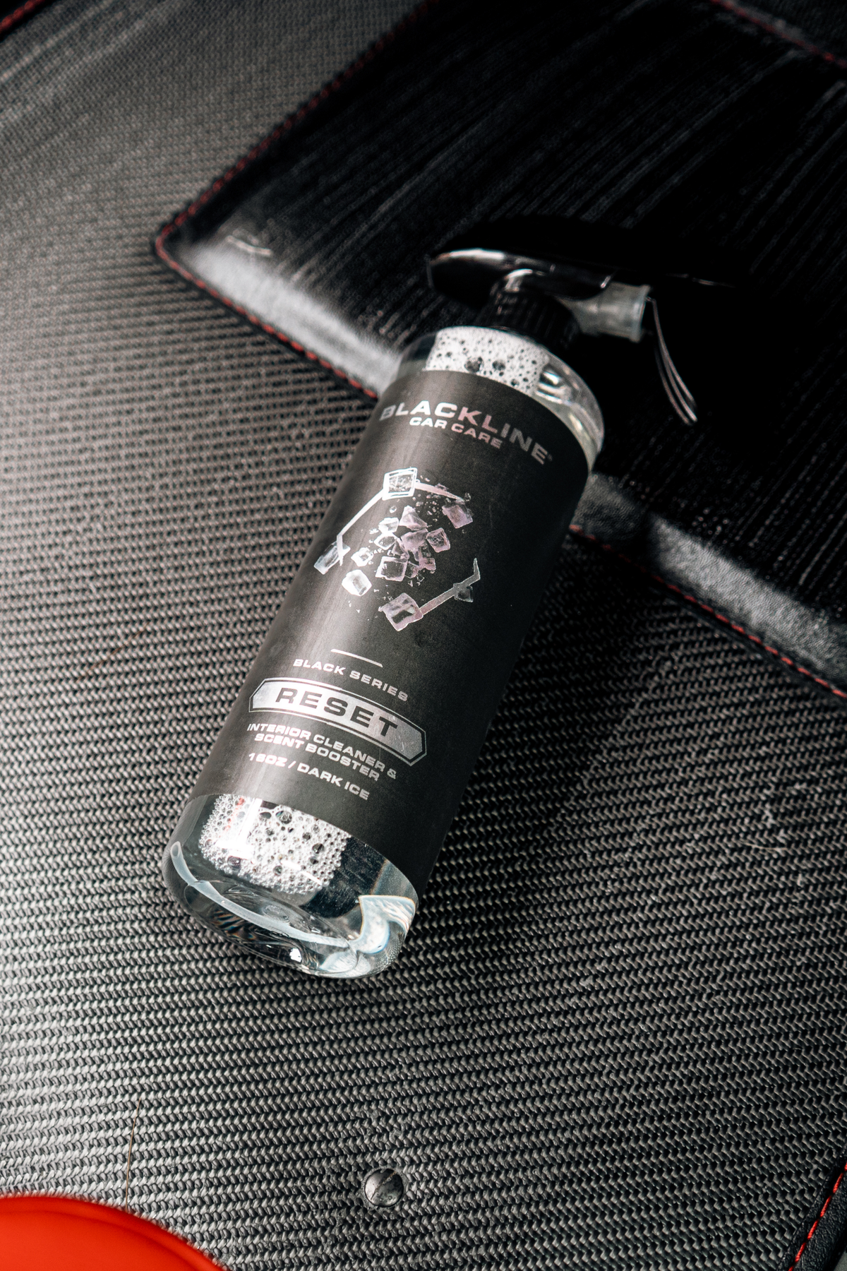 Blackline Reset Dark Ice interior cleaner being used on a car floor mat