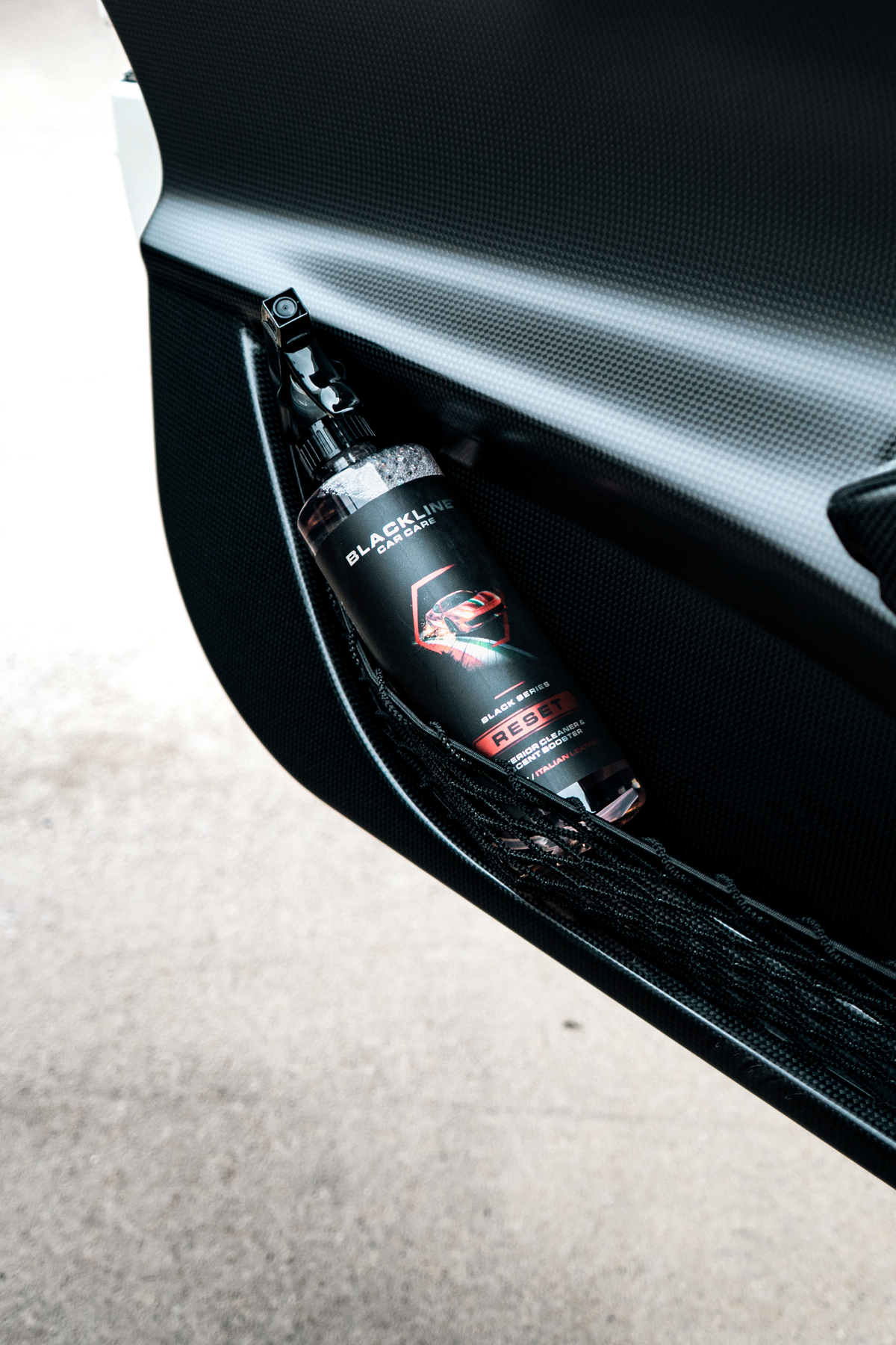 Blackline Reset Italian Leather interior cleaner applied to a car door panel.