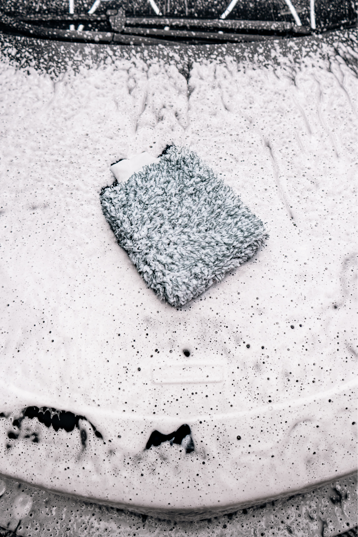 Lifestyle photo of the Blackline Microfiber Wash Mitt being used to wash a vehicle.