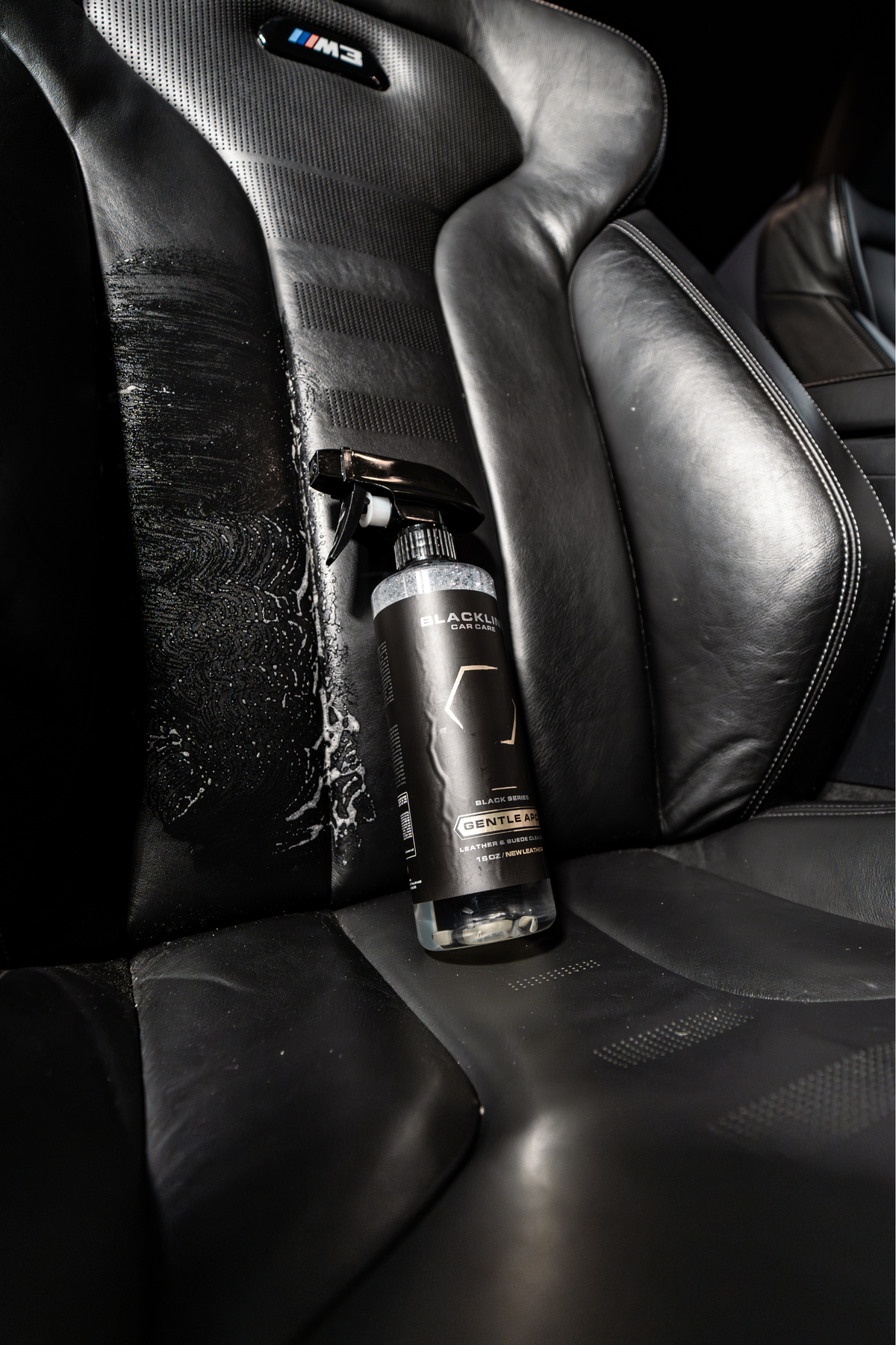 Blackline Gentle APC bottle resting on a leather car seat with a microfiber towel.